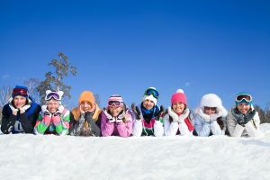 Group of teens lying on snow in ski resort